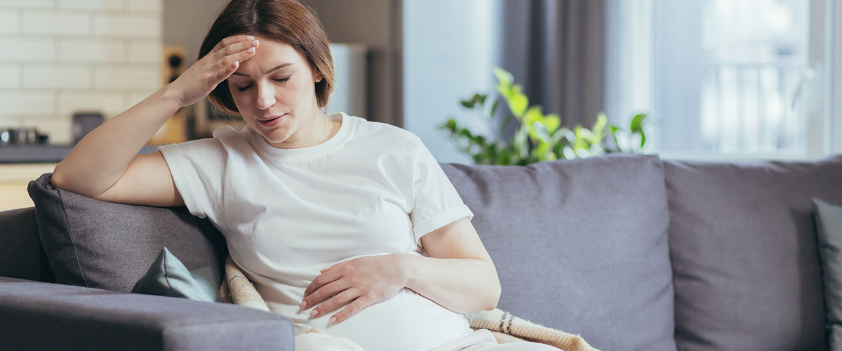 Pregnant woman sitting on sofa and feels pain